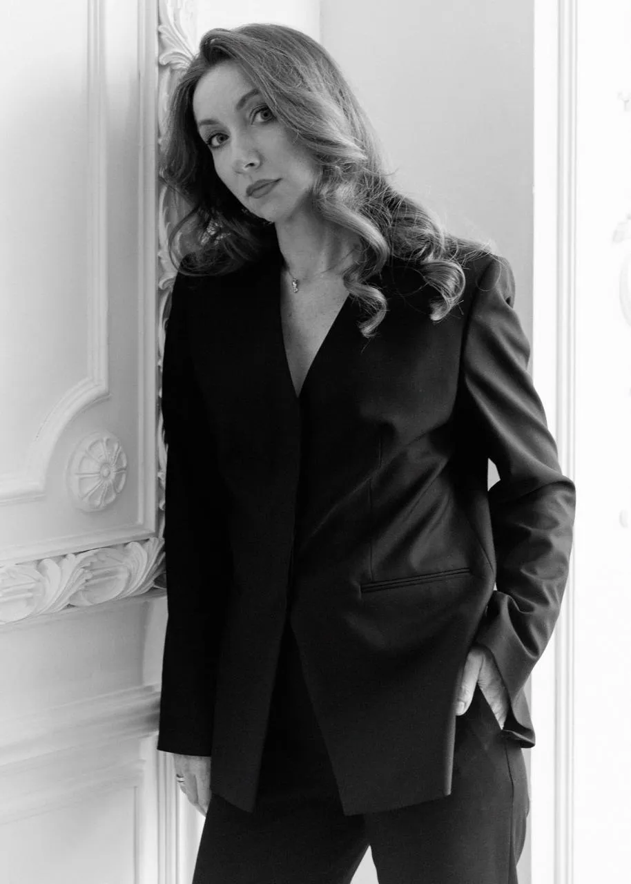 Portrait of Nadia Nazarova in a black blazer against a moulded wall